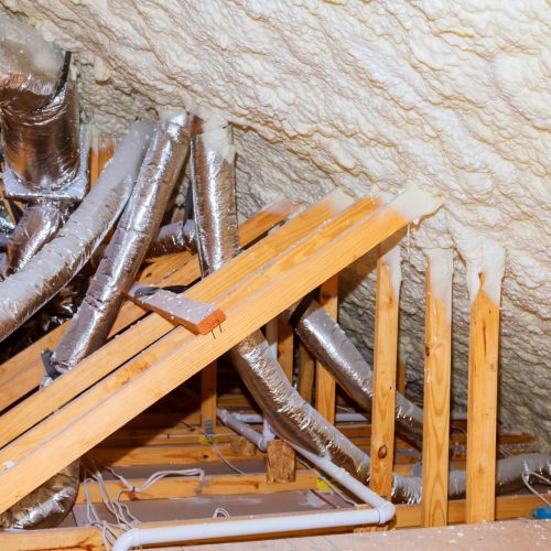 Insulation of attic with insulation material and pipe heating system a building with wooden beams of a roof structure