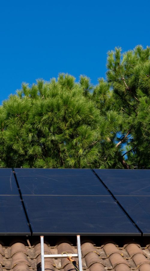 Technician working on photovoltaic panels on a roof with safety equipment